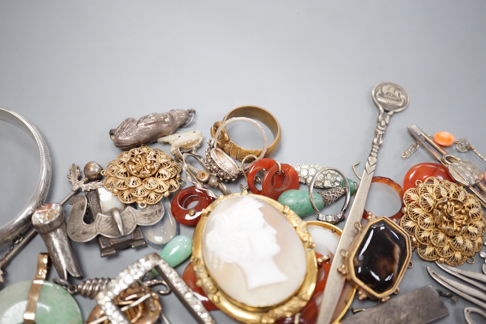 Assorted jewellery including jade pendant, yellow metal buckle brooch, modern silver hinged bangle, cameos, unmounted oval moonstone, agate set white metal buckle brooch, 800 standard paper knife etc.